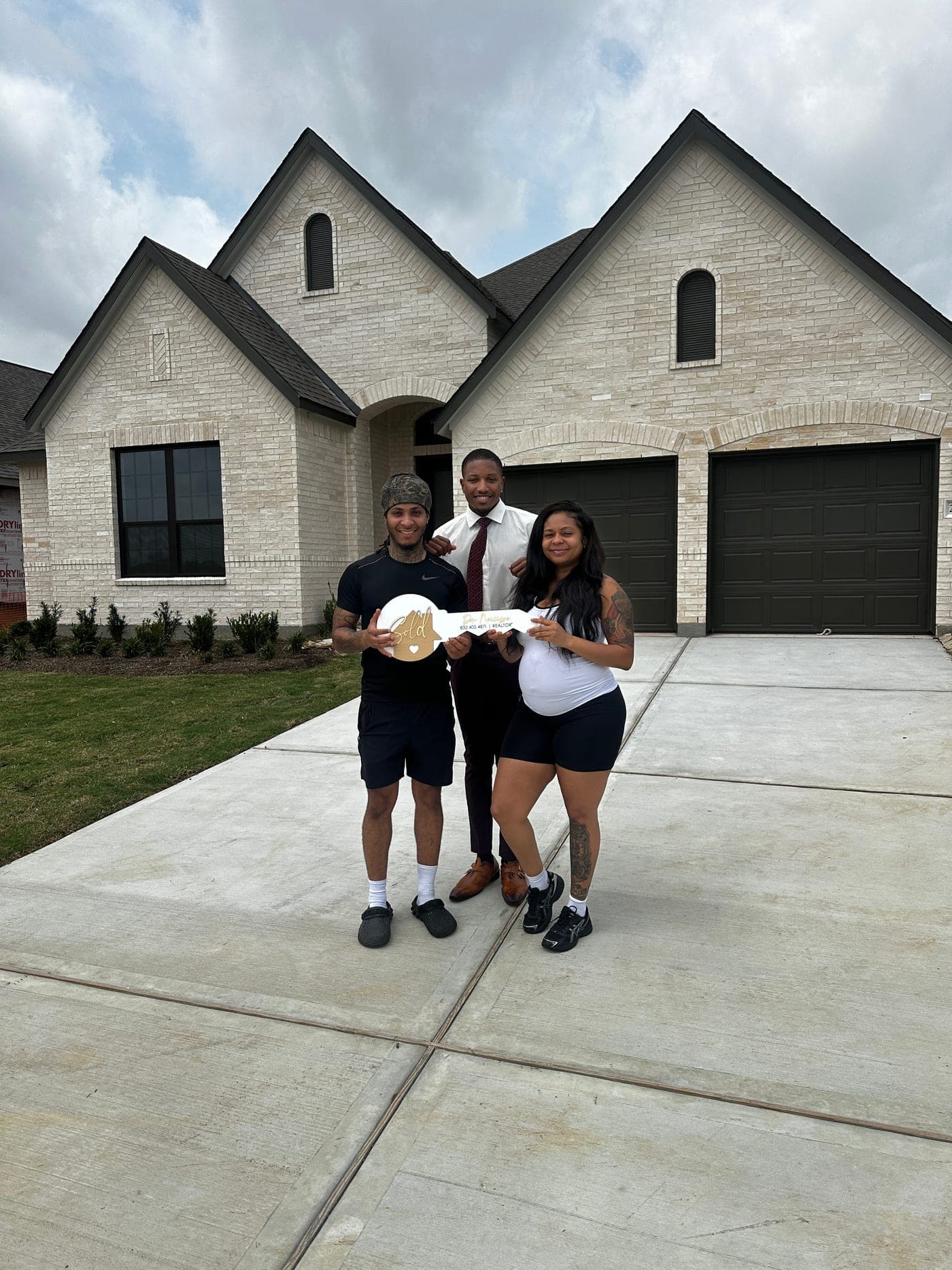 Don Narcisse with clients holding a sold key in front of their new home